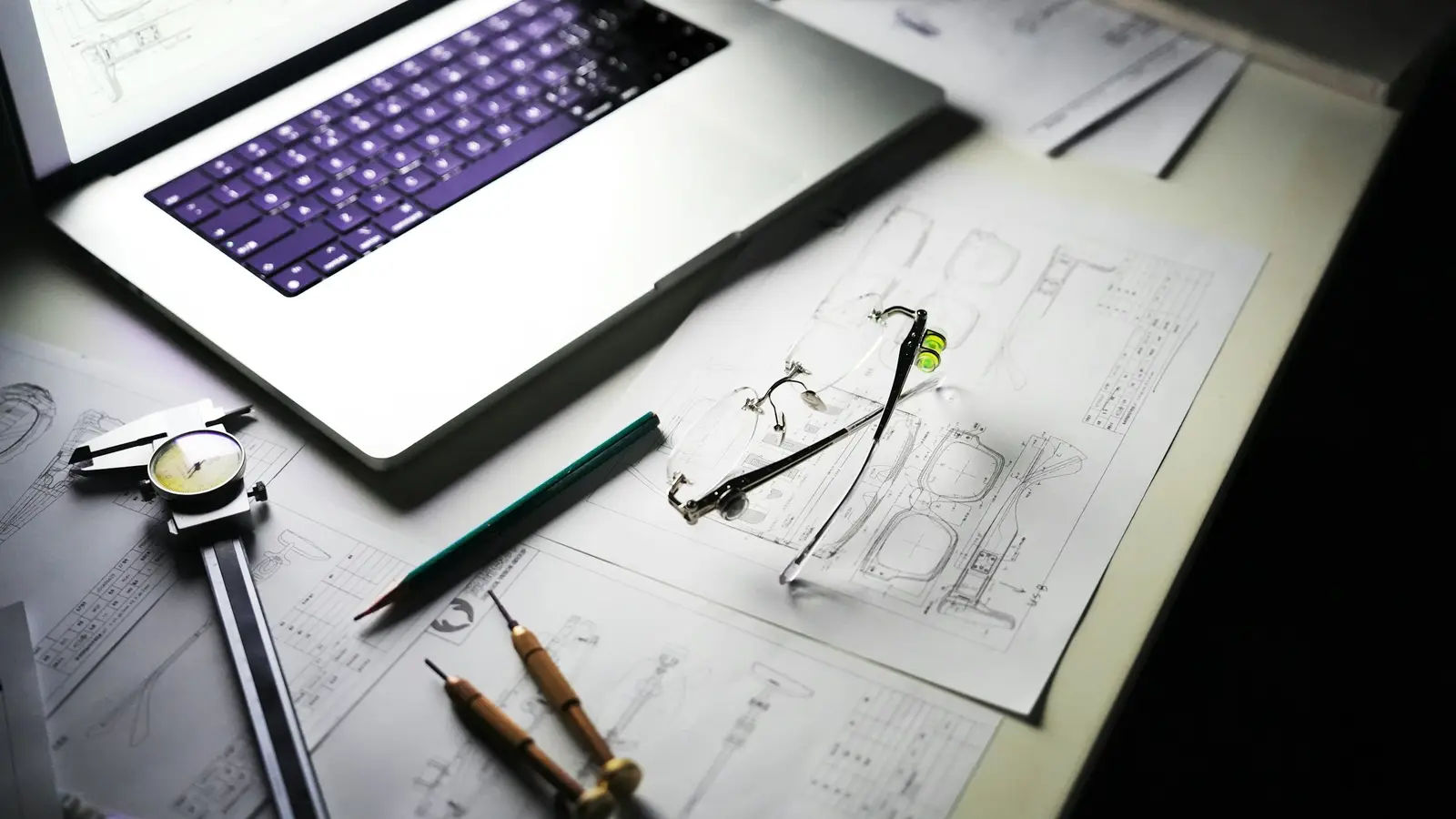 Desk with a laptop and blueprints for a custom home build