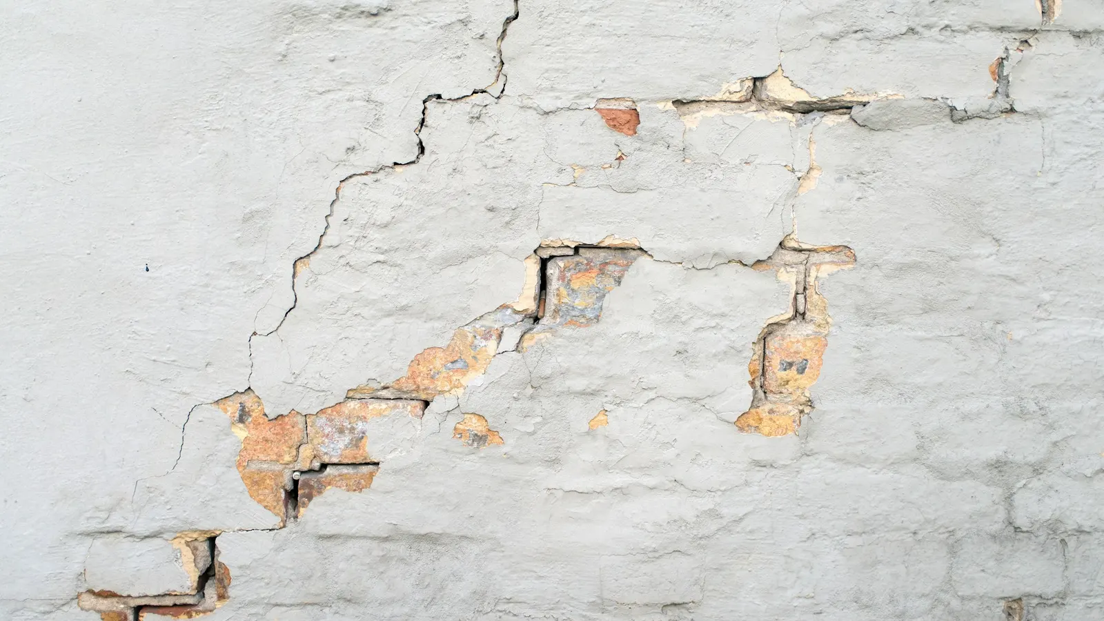 Cracked exterior brick wall on a residential foundation