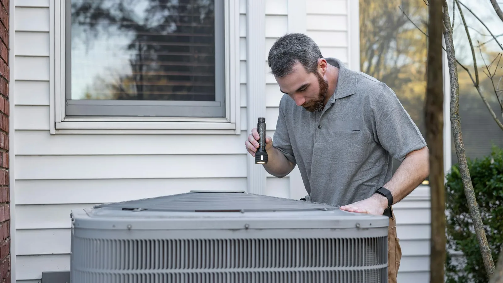 HVAC technician checking a service booking on a phone outside a customer home