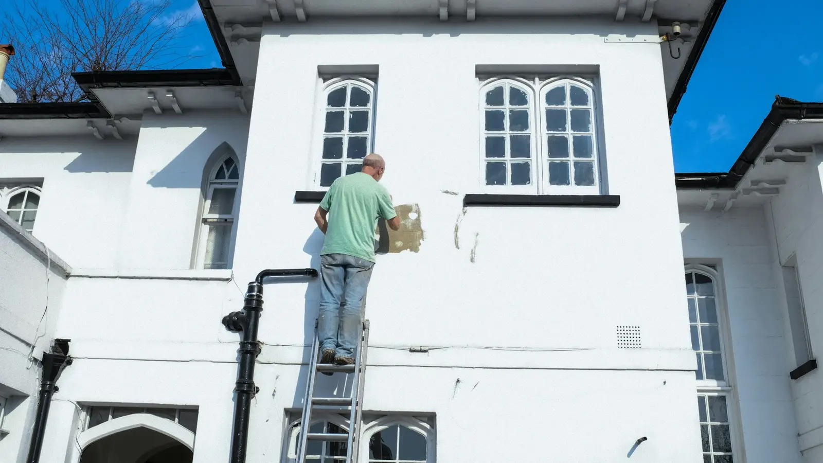 Painter on a ladder painting the exterior of a house