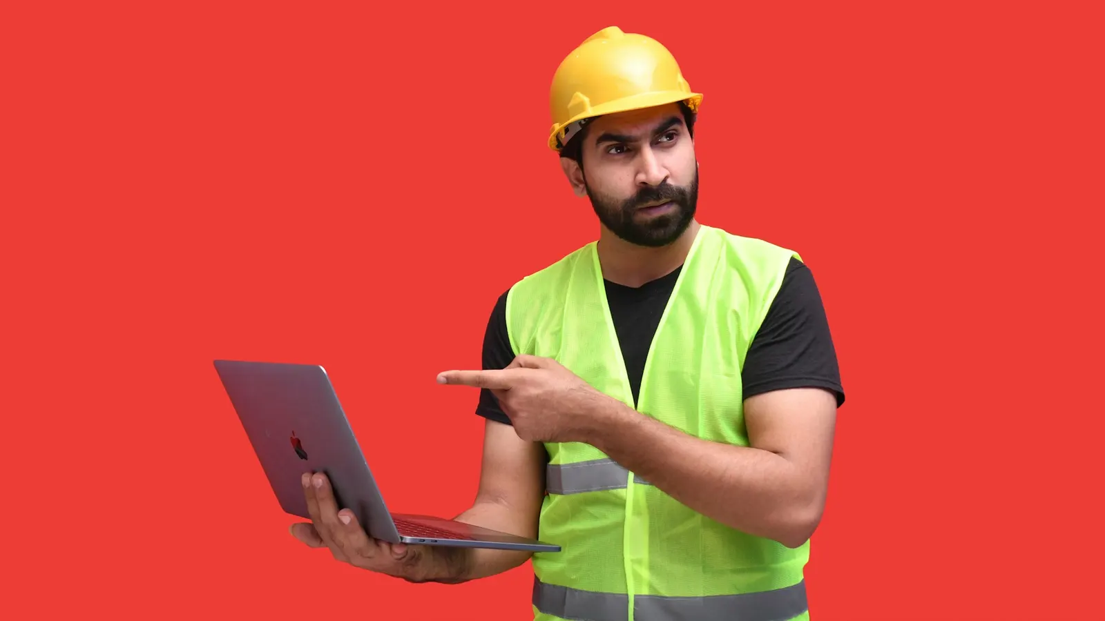 General contractor in a hard hat reviewing a laptop on an active remodeling jobsite