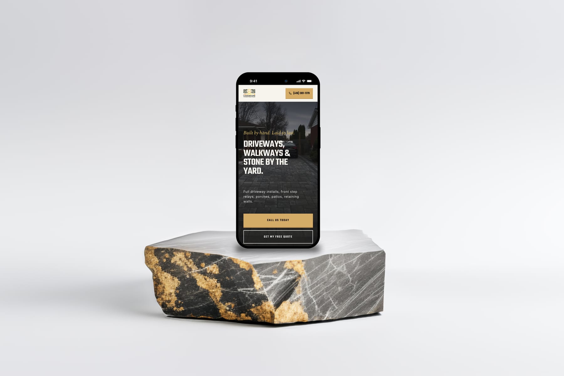 The new jeorgyslandscape.ca homepage open on an iPhone, held up in front of a finished stone paver driveway in Mississauga. The website where a homeowner actually opens it.