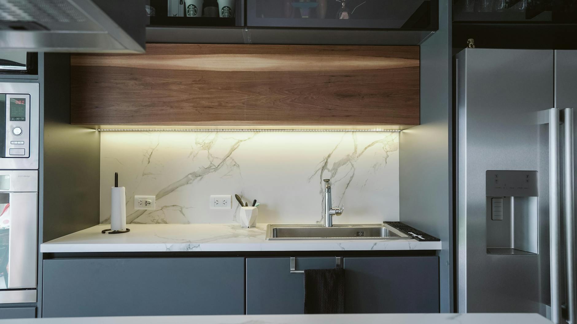 Sleek minimalist kitchen design featuring marble countertop and stainless steel appliances.