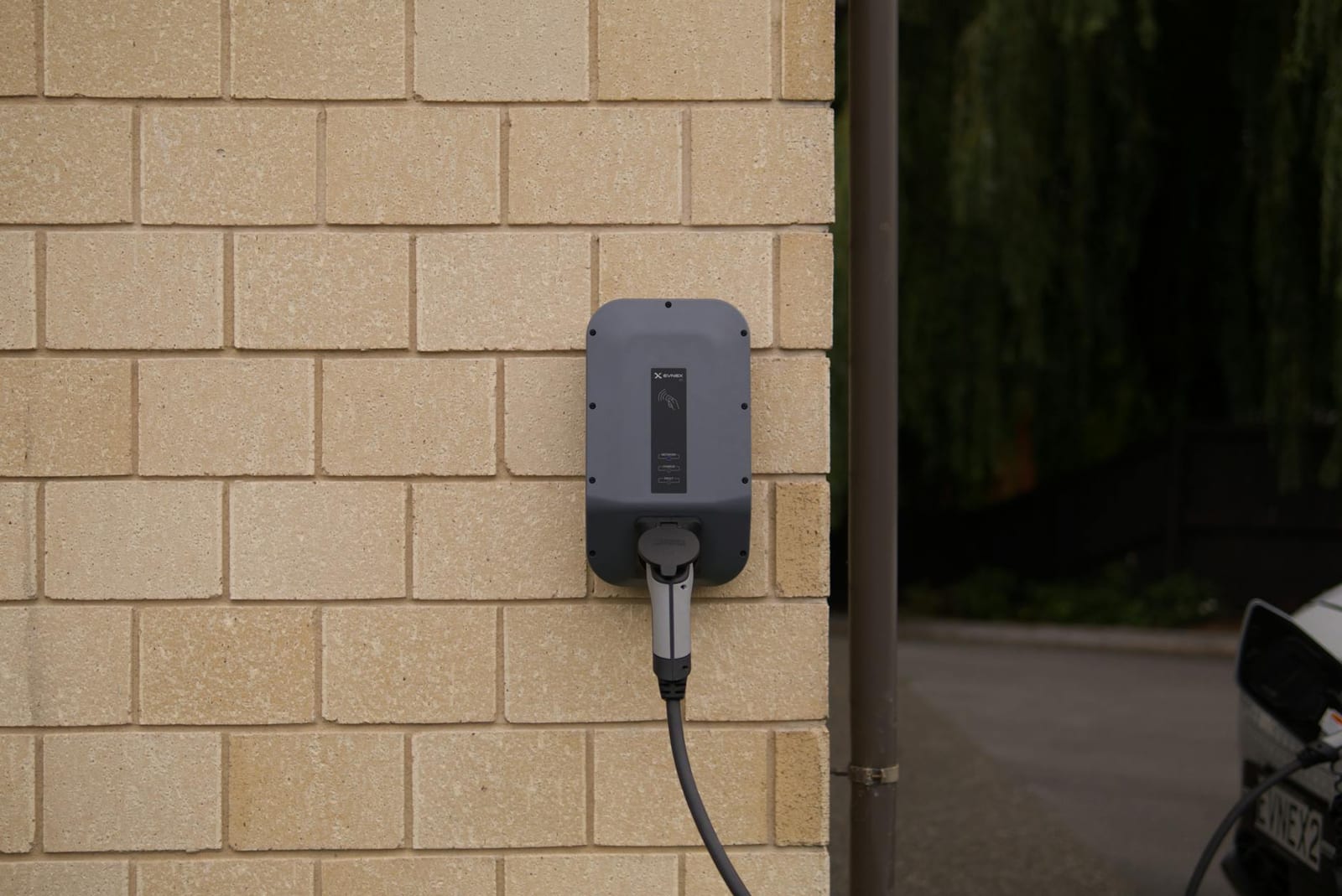 A wall-mounted electric vehicle charging station installed on a brick wall in Christchurch, New Zealand.