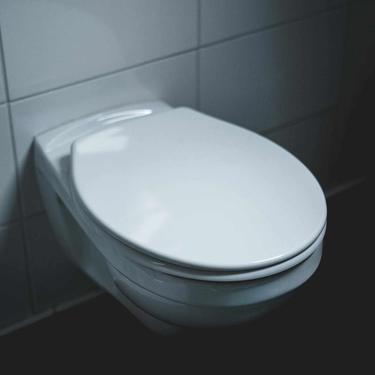 A sleek and modern white toilet in a well-lit minimalist bathroom setting.