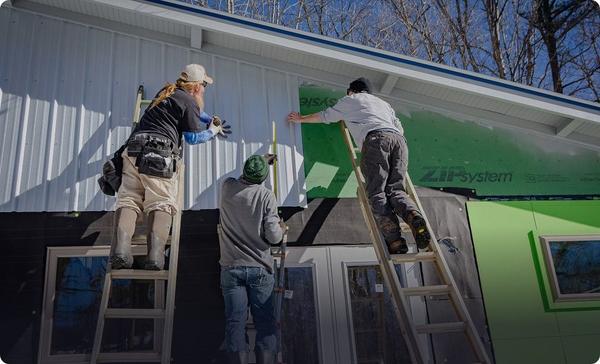 Siding crew installing exterior panels on ladders
